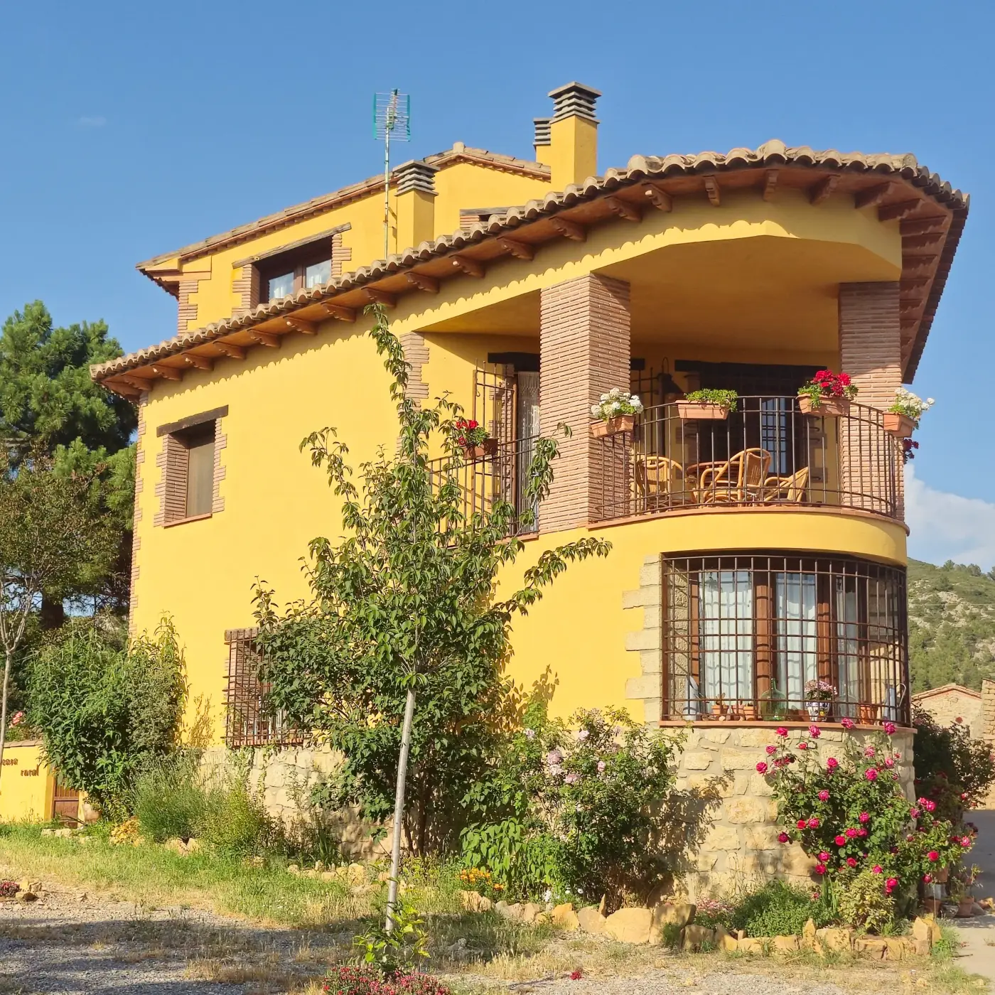 Fachada amarilla de La Canterica con su torre, balcones y rosales