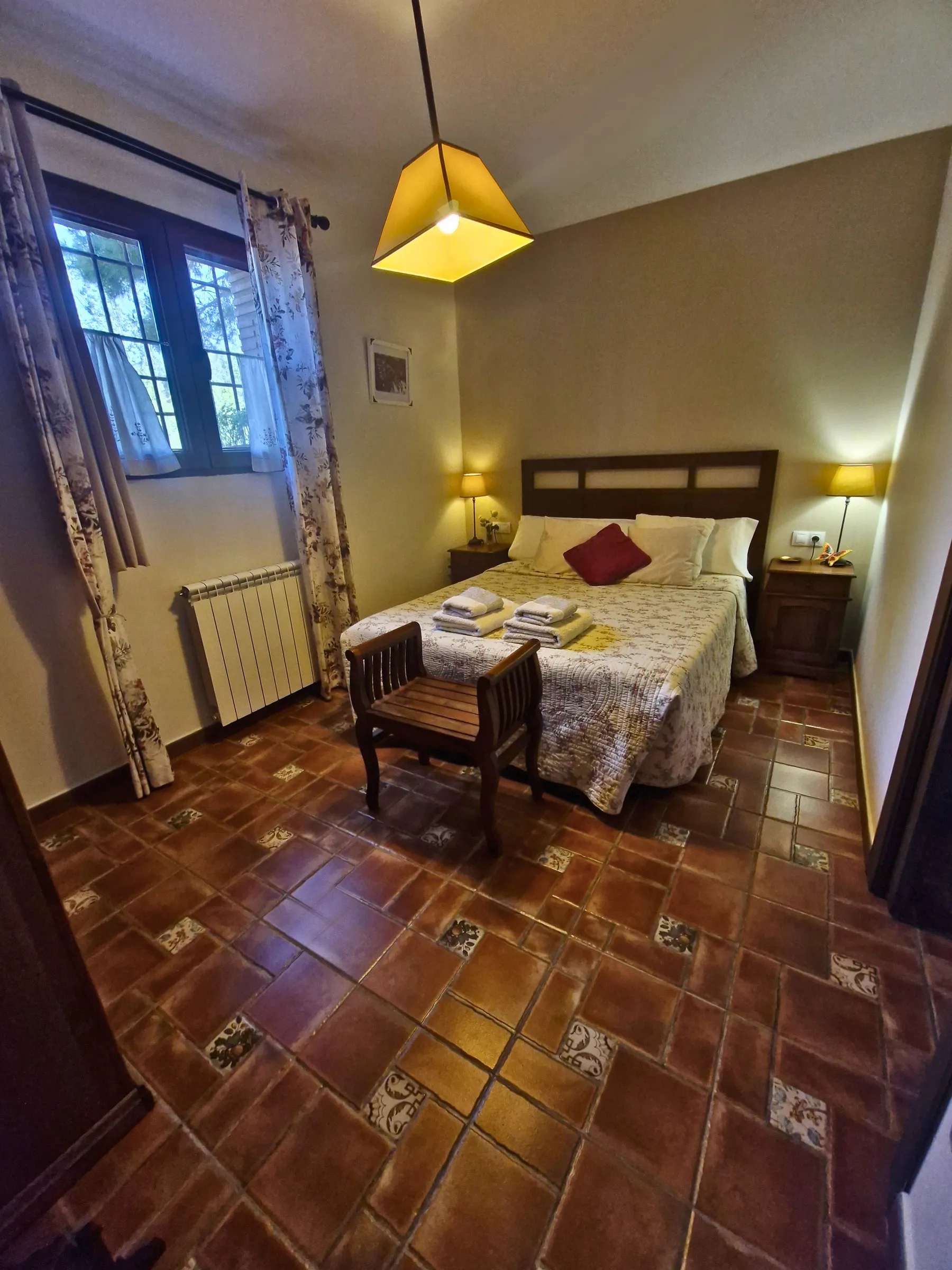 Dormitorio de matrimonio de El Jardín con cabecero de madera, mesillas y suelo de barro