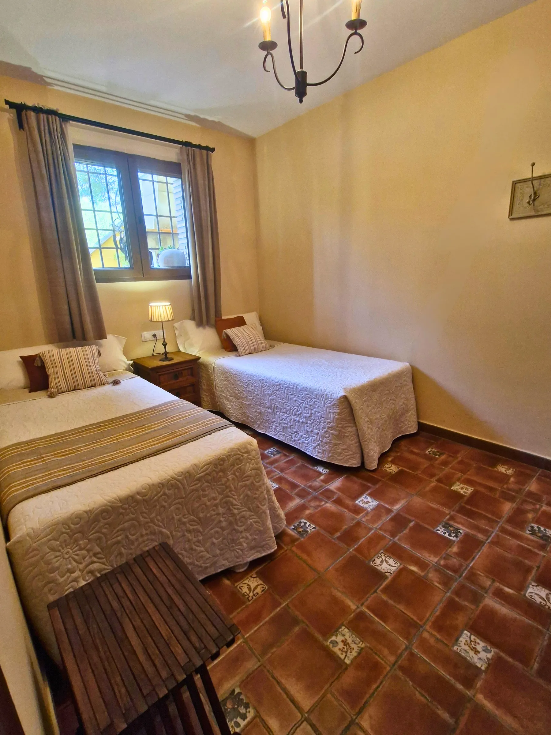 Dormitorio de El Jardín con dos camas individuales y ventana al jardín