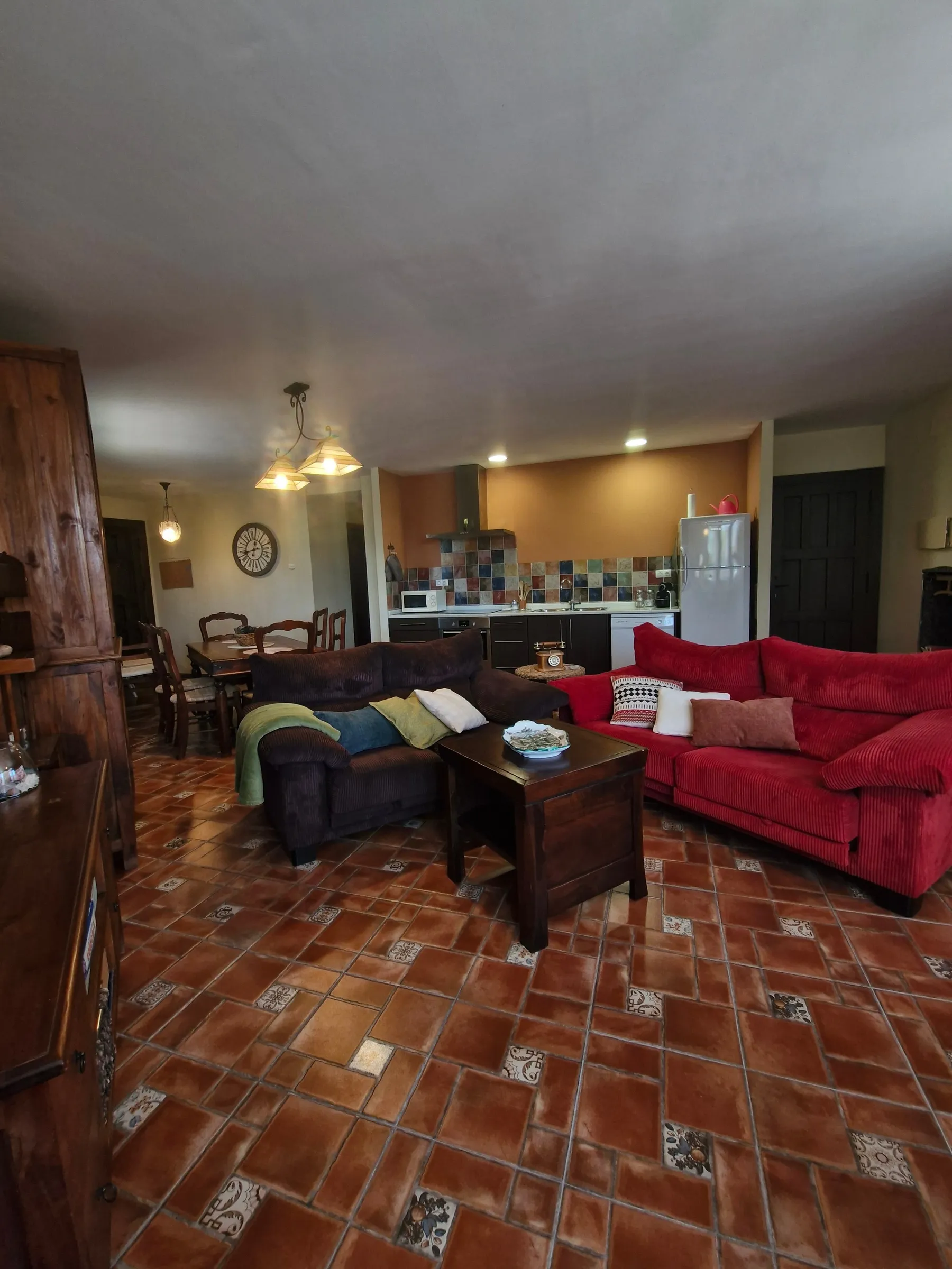 Salón-comedor de El Jardín abierto a la cocina con sofá rojo y mesa de centro