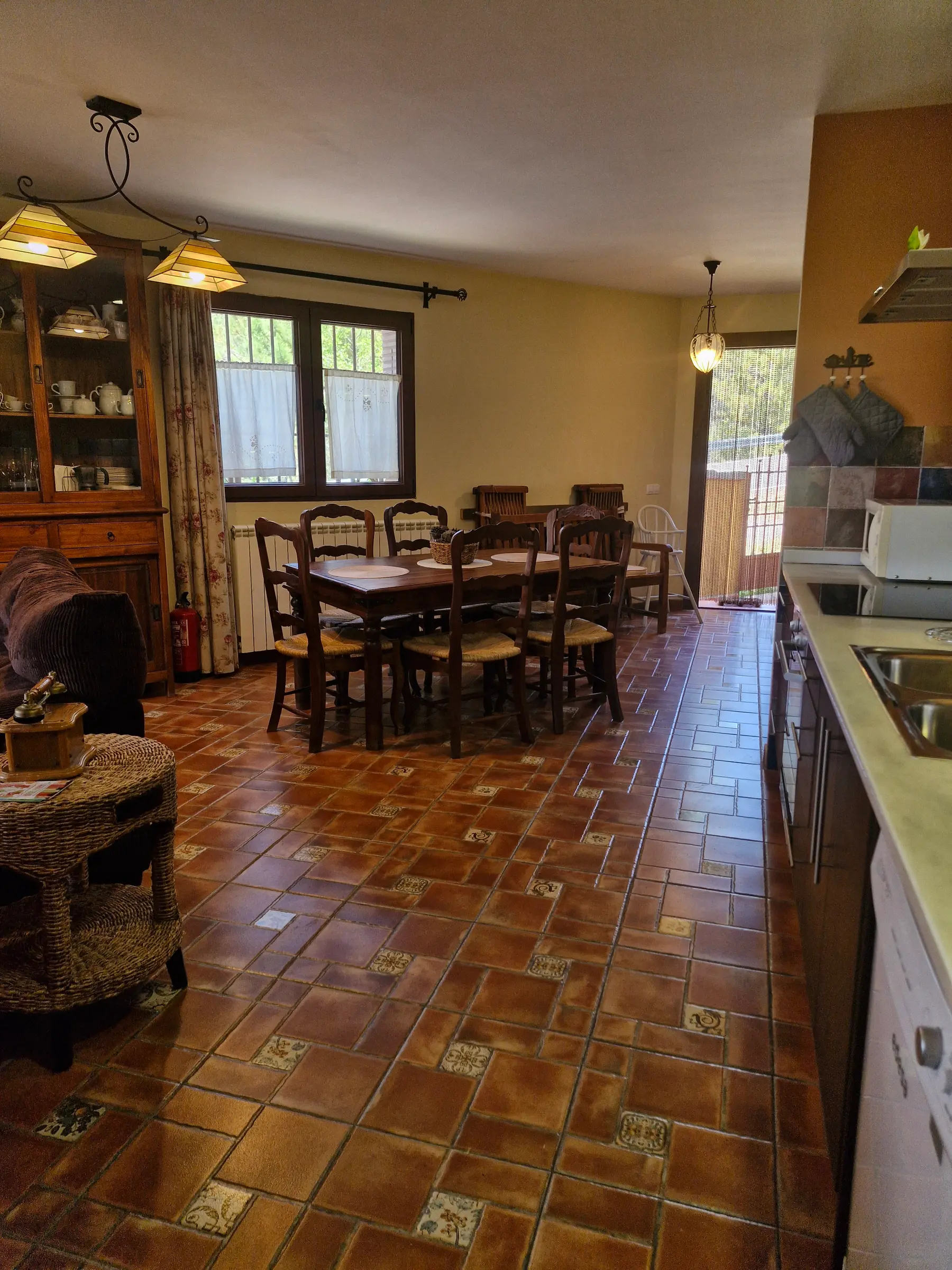 Cocina-comedor de El Jardín con mesa de madera y vitrina junto a la ventana
