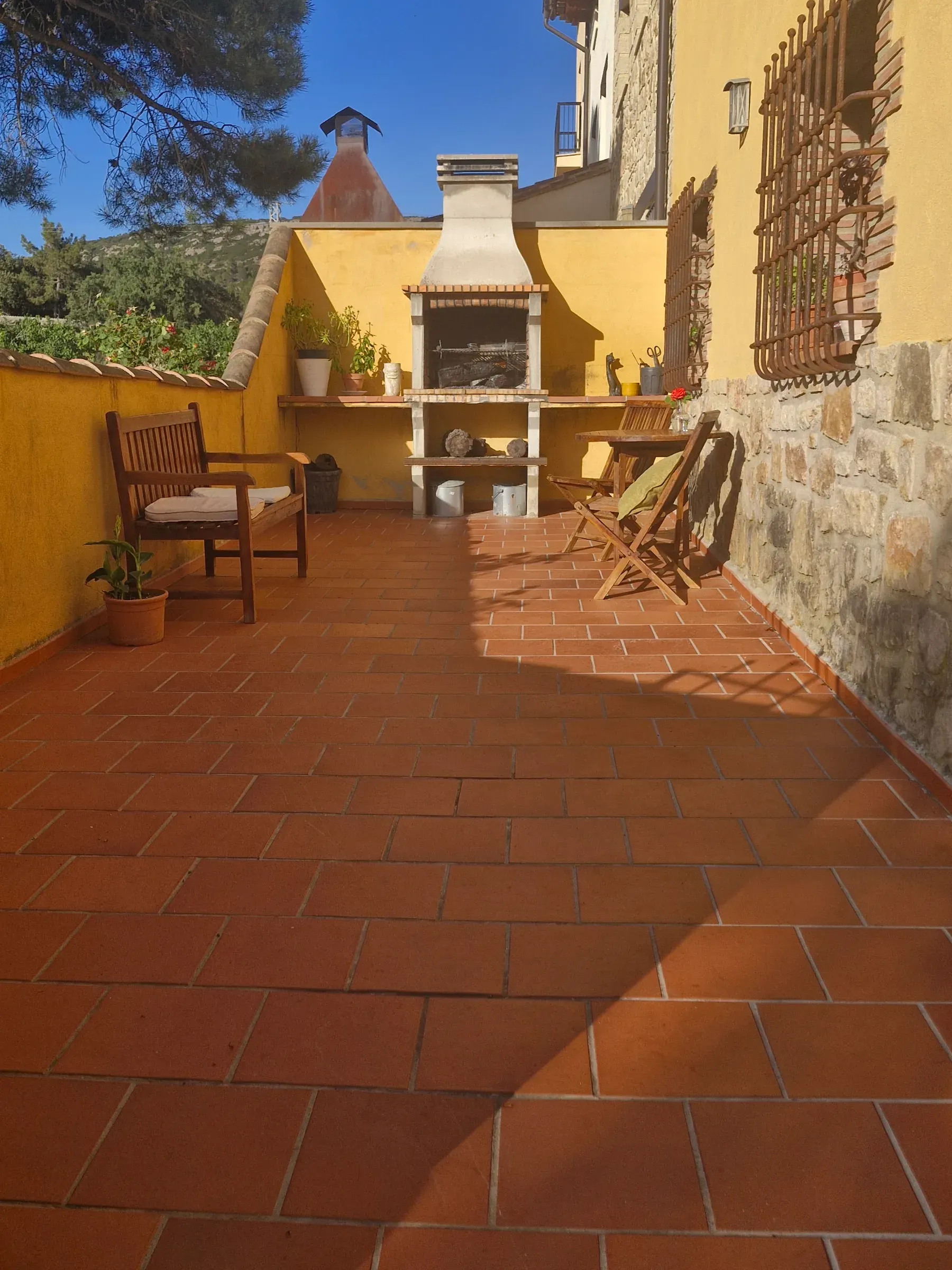 Terraza de El Jardín con barbacoa de obra y suelo de barro al sol