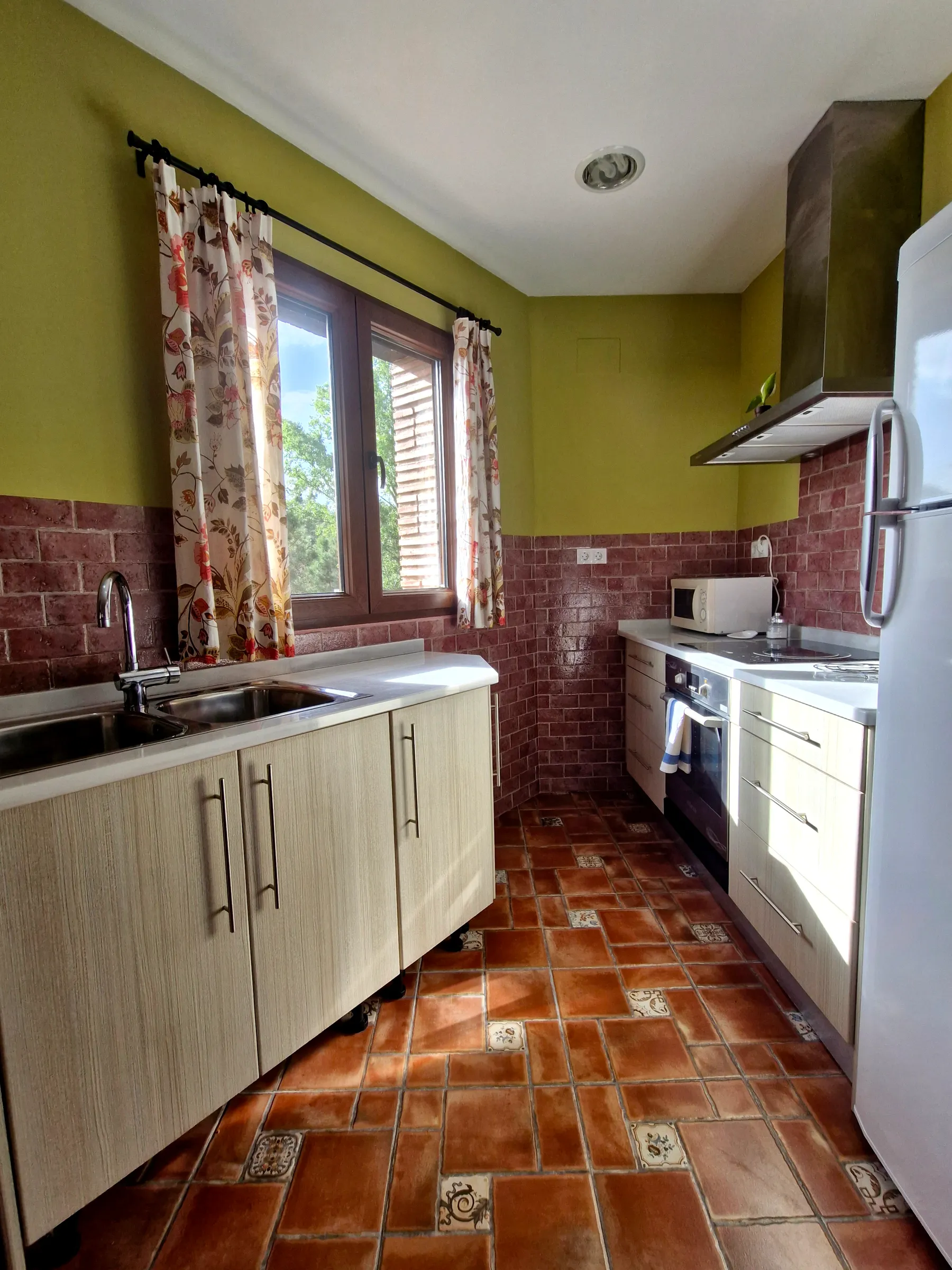 Cocina equipada de El Mirador con armarios blancos y ventana