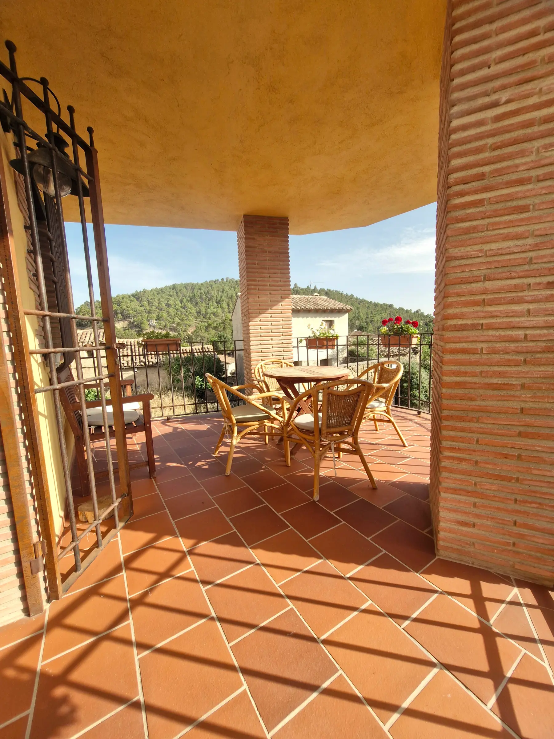 Terraza cubierta de El Mirador con mesa y sillas y vistas a la sierra