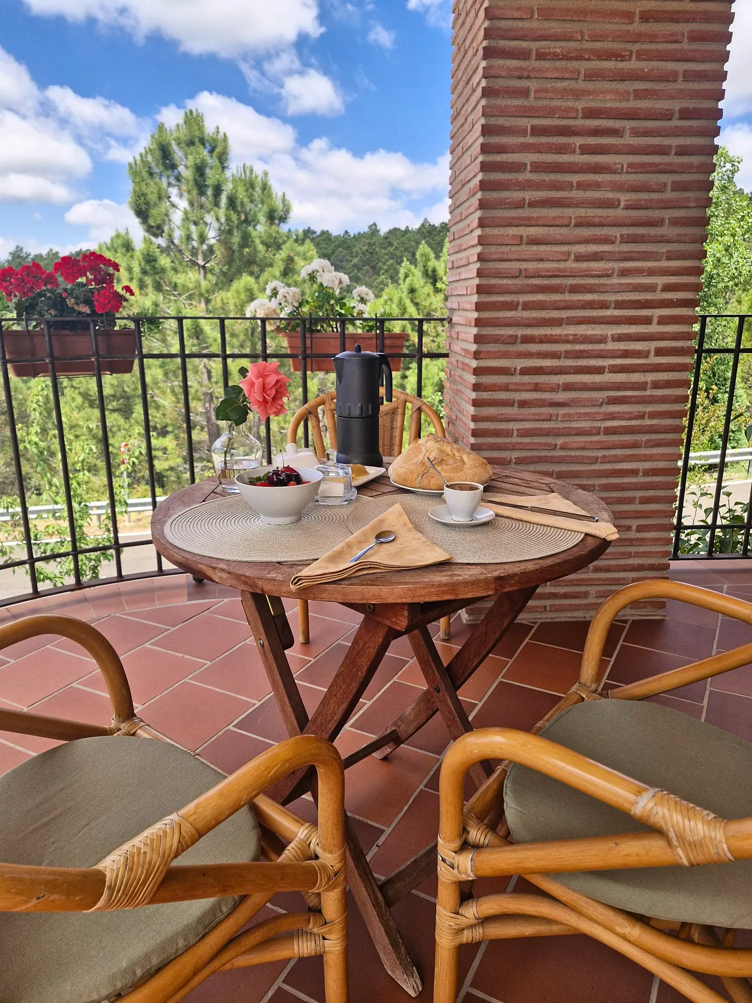 Terraza de El Mirador con mesa redonda y sillas de mimbre bajo el cielo azul